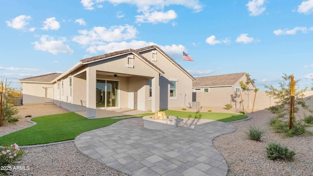 back of property with stucco siding, an outdoor fire pit, a fenced backyard, and a patio