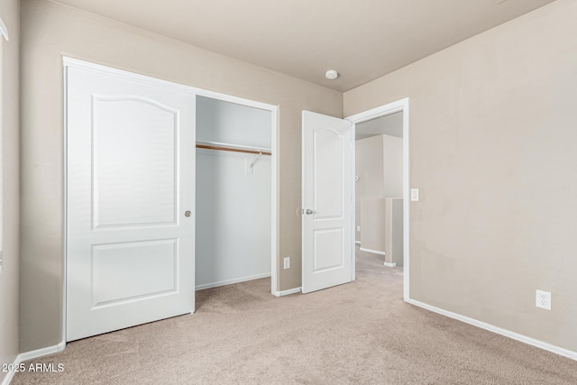unfurnished bedroom with baseboards, carpet, and a closet