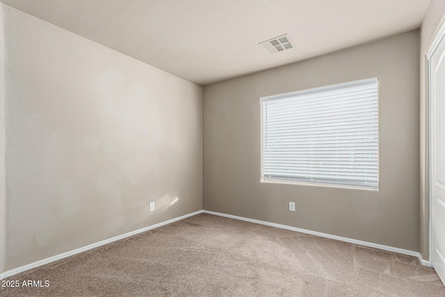 carpeted spare room featuring baseboards and visible vents
