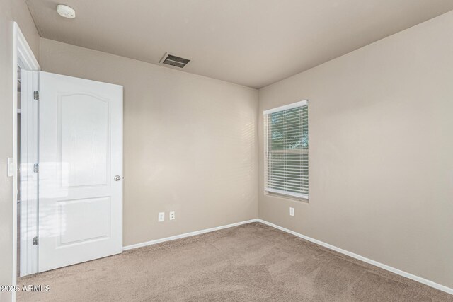 carpeted empty room featuring baseboards and visible vents