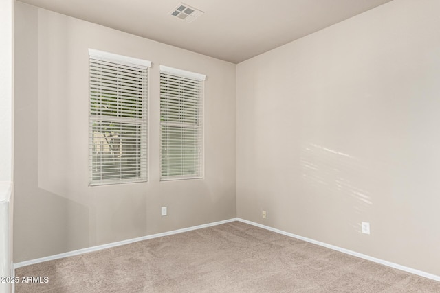 spare room with carpet floors, baseboards, and visible vents