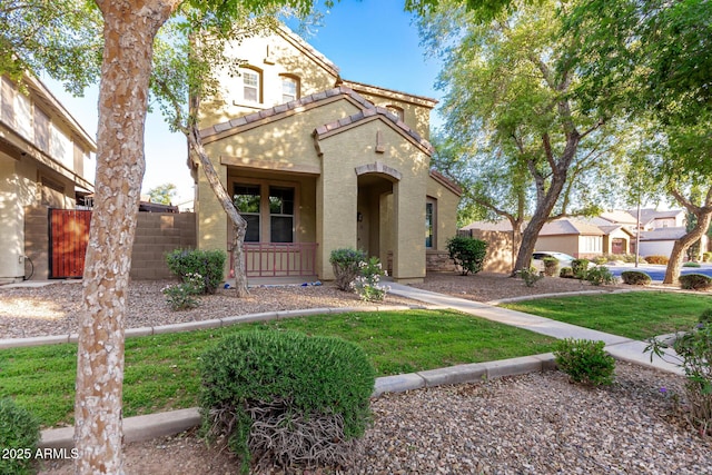 mediterranean / spanish house with stucco siding, a front yard, a tile roof, and fence