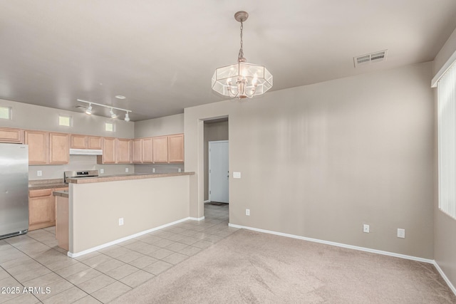 kitchen featuring light brown cabinetry, stainless steel appliances, light tile patterned floors, under cabinet range hood, and visible vents