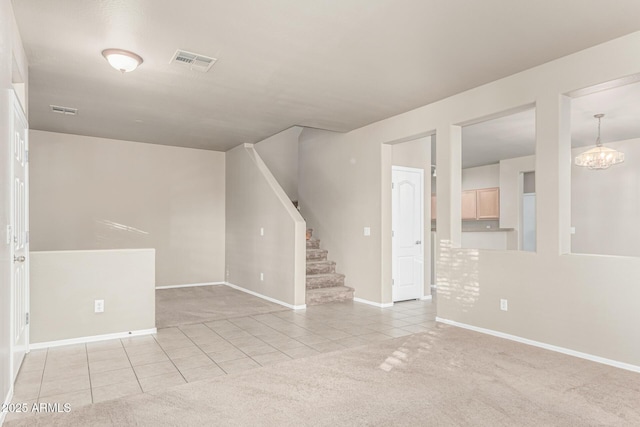 carpeted empty room featuring stairs, baseboards, visible vents, and tile patterned flooring