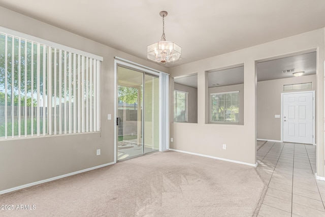carpeted empty room with an inviting chandelier, baseboards, and tile patterned flooring