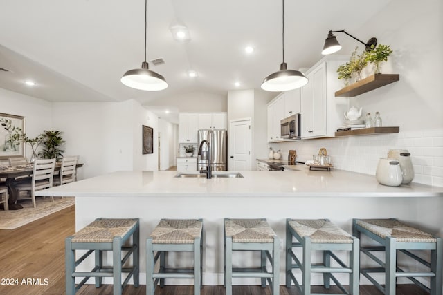 kitchen with kitchen peninsula, pendant lighting, a breakfast bar area, white cabinets, and appliances with stainless steel finishes