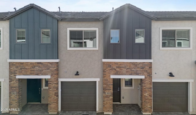 townhome / multi-family property featuring stone siding, stucco siding, board and batten siding, and a garage