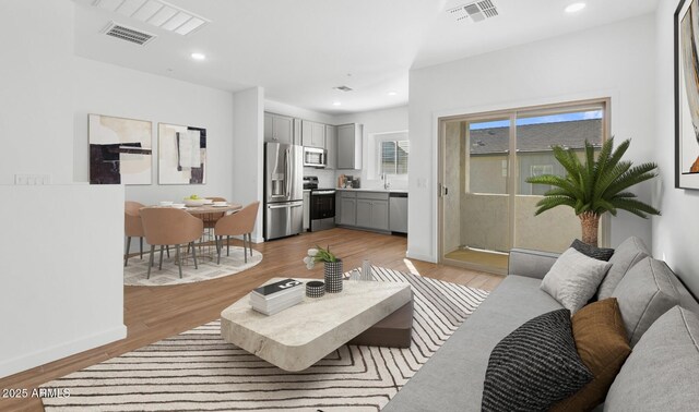 living room with recessed lighting, visible vents, and light wood finished floors