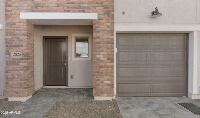 doorway to property with a garage and brick siding