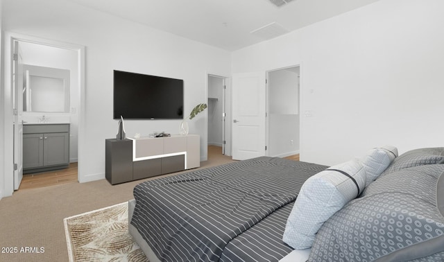 bedroom featuring visible vents, light carpet, ensuite bathroom, a sink, and baseboards