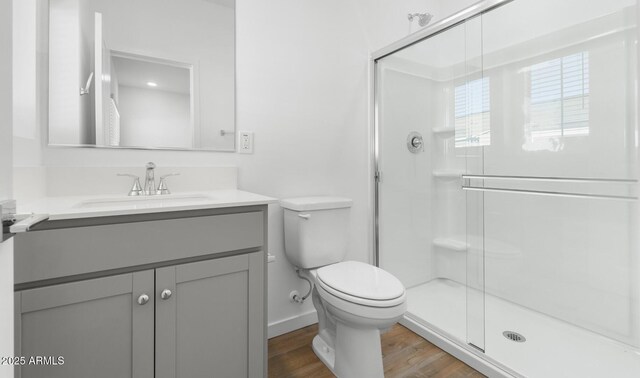 full bathroom featuring toilet, a stall shower, wood finished floors, baseboards, and vanity