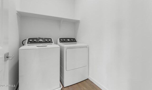 clothes washing area with washer and dryer, laundry area, light wood-style flooring, and baseboards