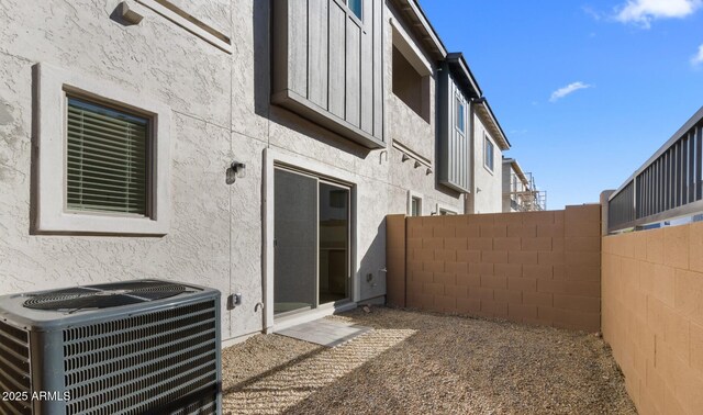 exterior space featuring stucco siding, central AC unit, and fence