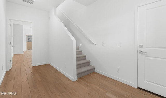 staircase featuring visible vents, baseboards, and wood finished floors