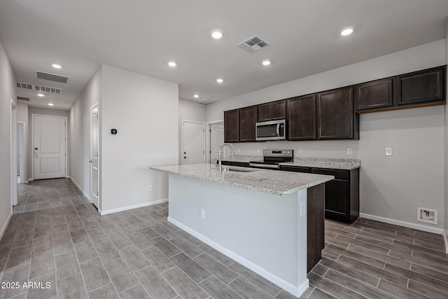 2514 E Music Mountain Ave, Apache Junction, AZ 85119 - kitchen featuring stainless steel appliances, a sink, dark brown cabinets, a kitchen island with sink, and wood finish floors