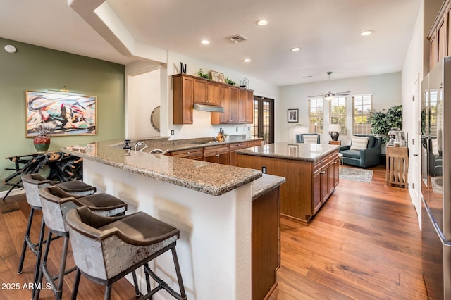 kitchen featuring pendant lighting, kitchen peninsula, light hardwood / wood-style floors, and a breakfast bar area