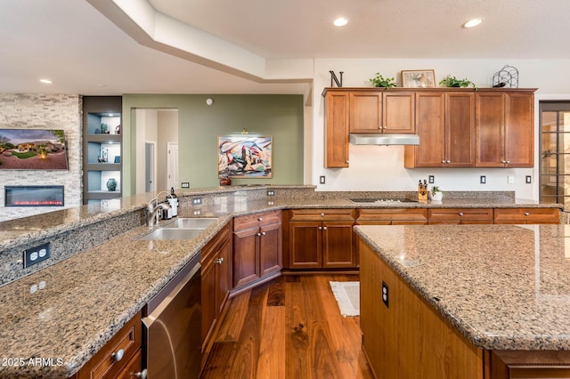 kitchen with sink, dark wood-type flooring, black electric stovetop, a fireplace, and stainless steel dishwasher