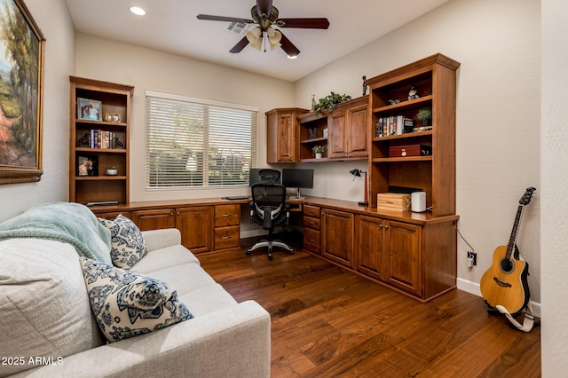 office space featuring ceiling fan, built in desk, and dark hardwood / wood-style flooring