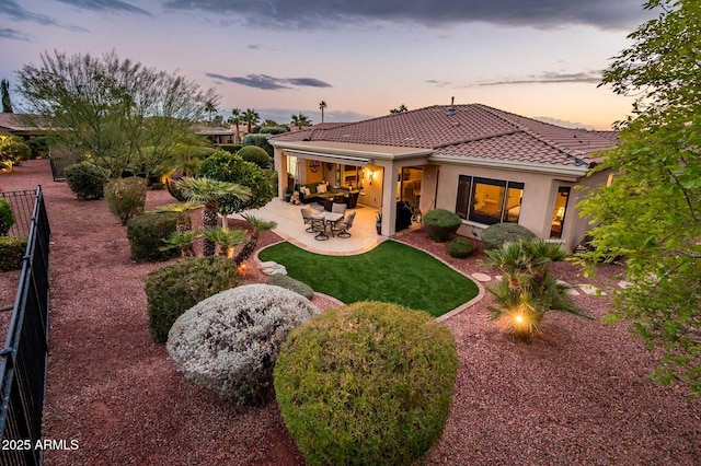 back house at dusk with a patio area