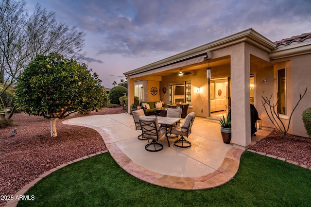 patio terrace at dusk featuring an outdoor living space and ceiling fan