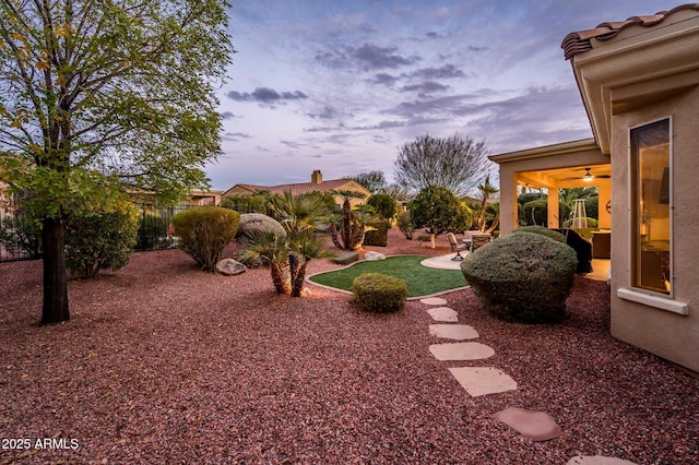 yard at dusk with a patio and ceiling fan