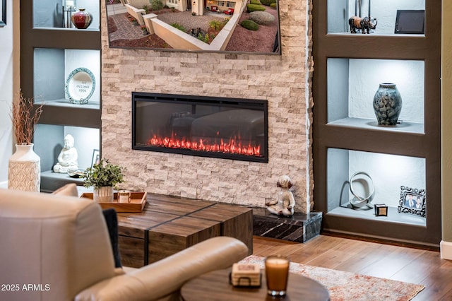 living room featuring wood-type flooring and a stone fireplace