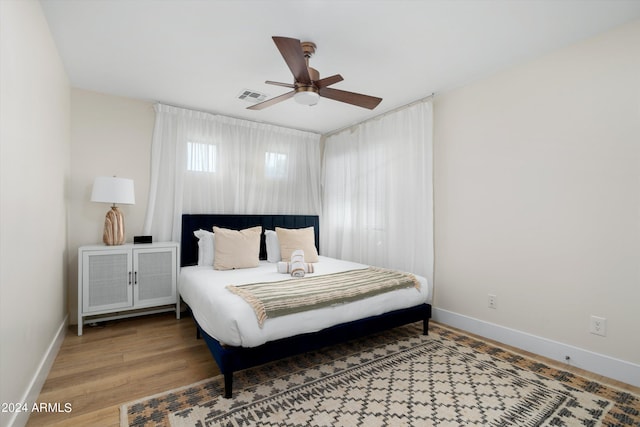 bedroom with visible vents, baseboards, wood finished floors, and a ceiling fan