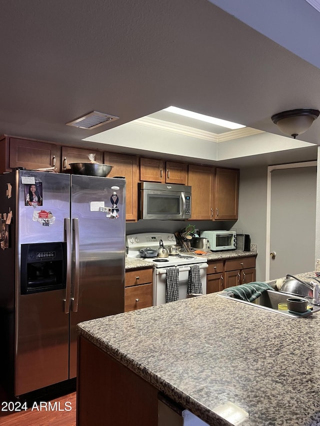 kitchen with crown molding, appliances with stainless steel finishes, and a tray ceiling