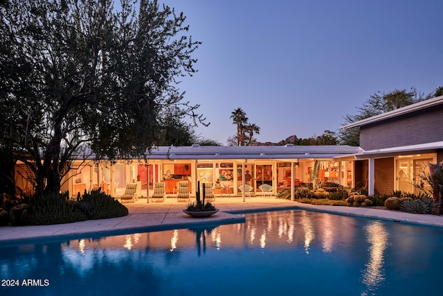 pool at dusk featuring a patio area