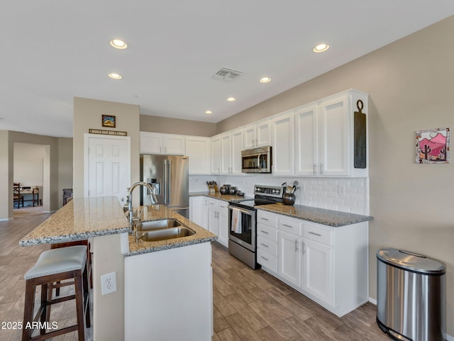 kitchen with stainless steel appliances, tasteful backsplash, a sink, and visible vents