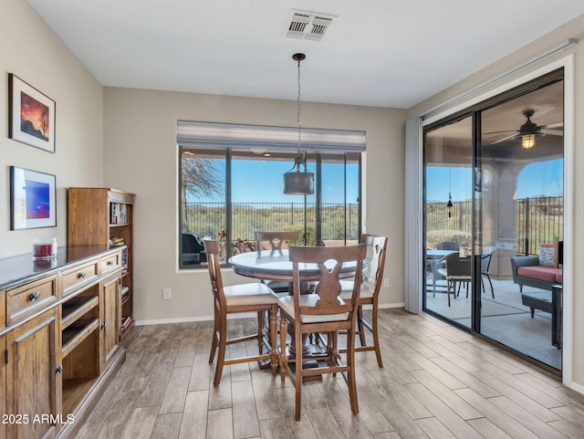 dining space featuring light wood-type flooring, visible vents, and baseboards