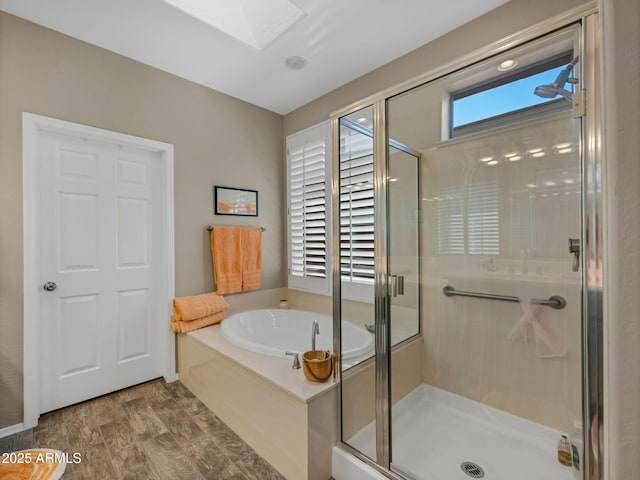 full bathroom with wood finished floors, a skylight, a shower stall, and a bath