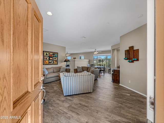 living room with ceiling fan, baseboards, and wood finished floors