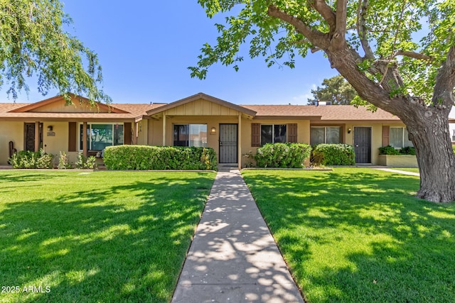 ranch-style home with a shingled roof and a front lawn