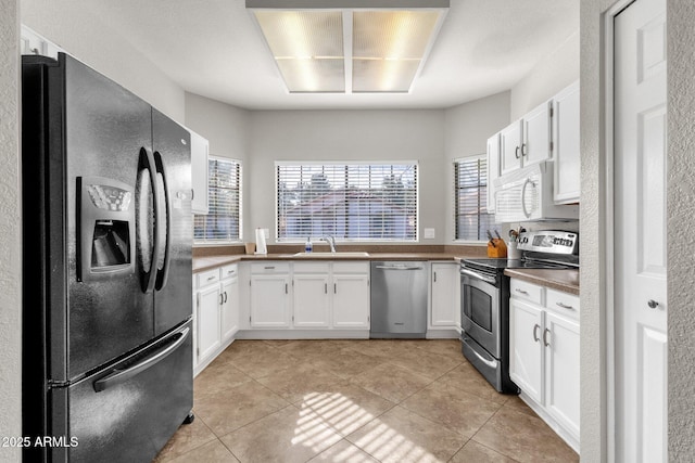 kitchen with white cabinetry, light tile patterned floors, stainless steel appliances, and sink