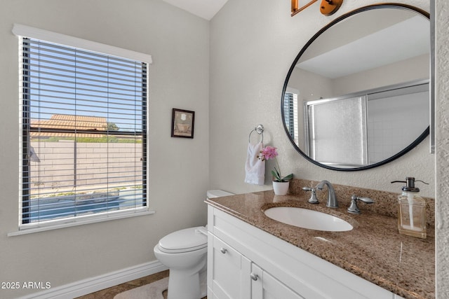 bathroom with vanity, toilet, and a shower with door