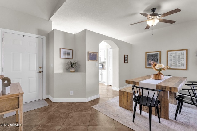 tiled dining area with ceiling fan and lofted ceiling