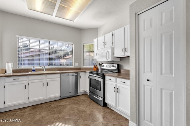 kitchen featuring stainless steel appliances, sink, light tile patterned floors, and white cabinets