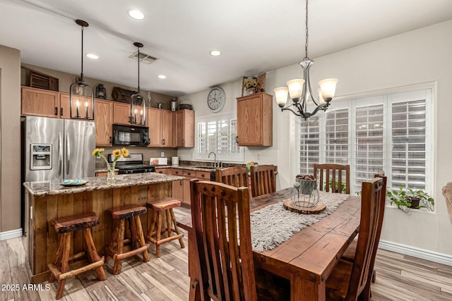 dining room featuring visible vents, light wood finished floors, baseboards, and a notable chandelier