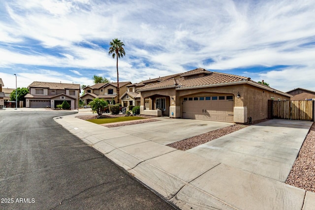 mediterranean / spanish-style home with fence, a tiled roof, concrete driveway, stucco siding, and a garage