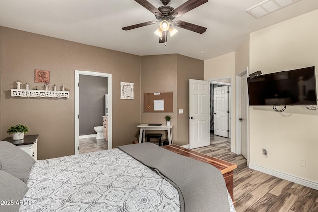 bedroom with wood finished floors, visible vents, baseboards, and connected bathroom