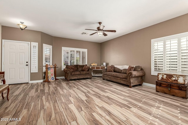 living room featuring baseboards, a ceiling fan, light wood-style floors, and visible vents