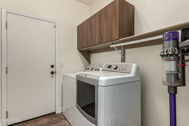 clothes washing area featuring washing machine and clothes dryer and cabinet space