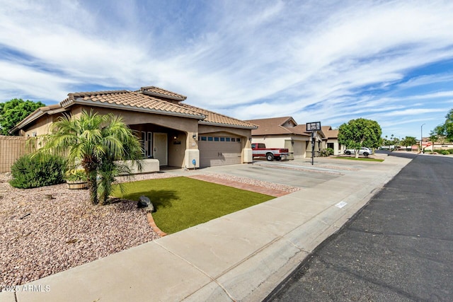 mediterranean / spanish home with an attached garage, a tiled roof, concrete driveway, and stucco siding