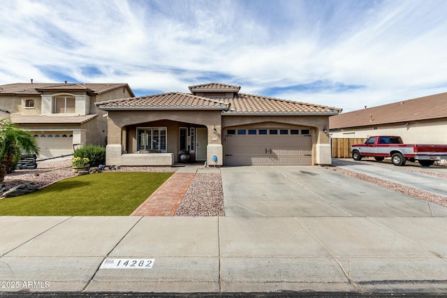 mediterranean / spanish house featuring a tile roof, a garage, driveway, a front yard, and stucco siding