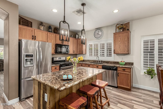 kitchen featuring light wood finished floors, dark stone countertops, visible vents, a sink, and appliances with stainless steel finishes