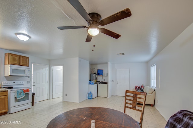 dining area with visible vents, baseboards, washer and clothes dryer, light tile patterned floors, and a textured ceiling