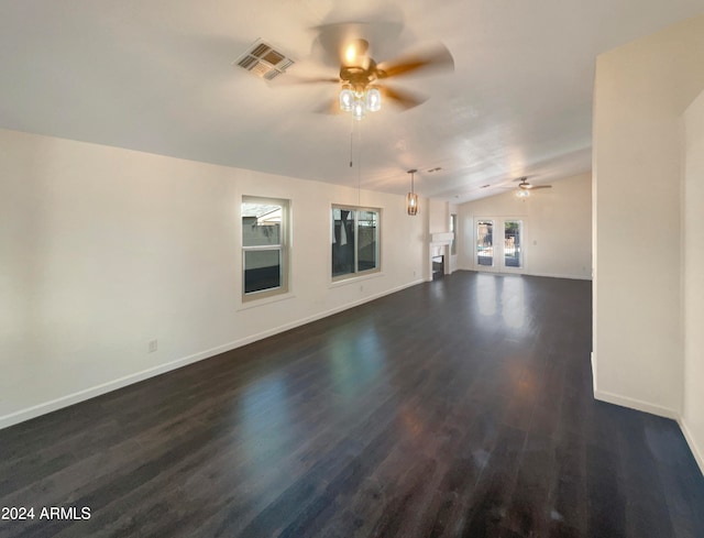 unfurnished living room with ceiling fan, vaulted ceiling, and dark wood-type flooring