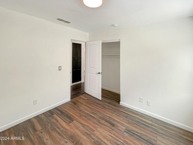 unfurnished living room with a notable chandelier, dark hardwood / wood-style flooring, and lofted ceiling