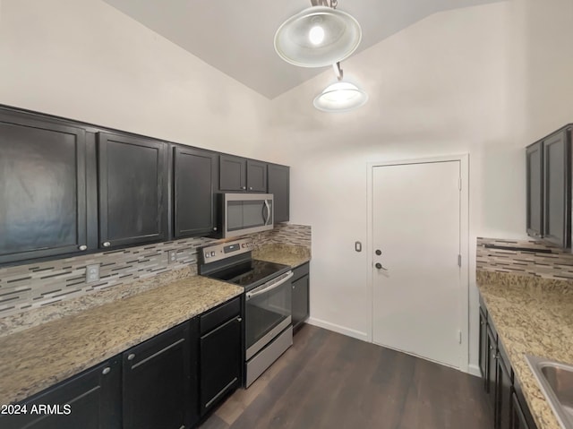 kitchen featuring appliances with stainless steel finishes, vaulted ceiling, decorative backsplash, dark hardwood / wood-style floors, and light stone countertops